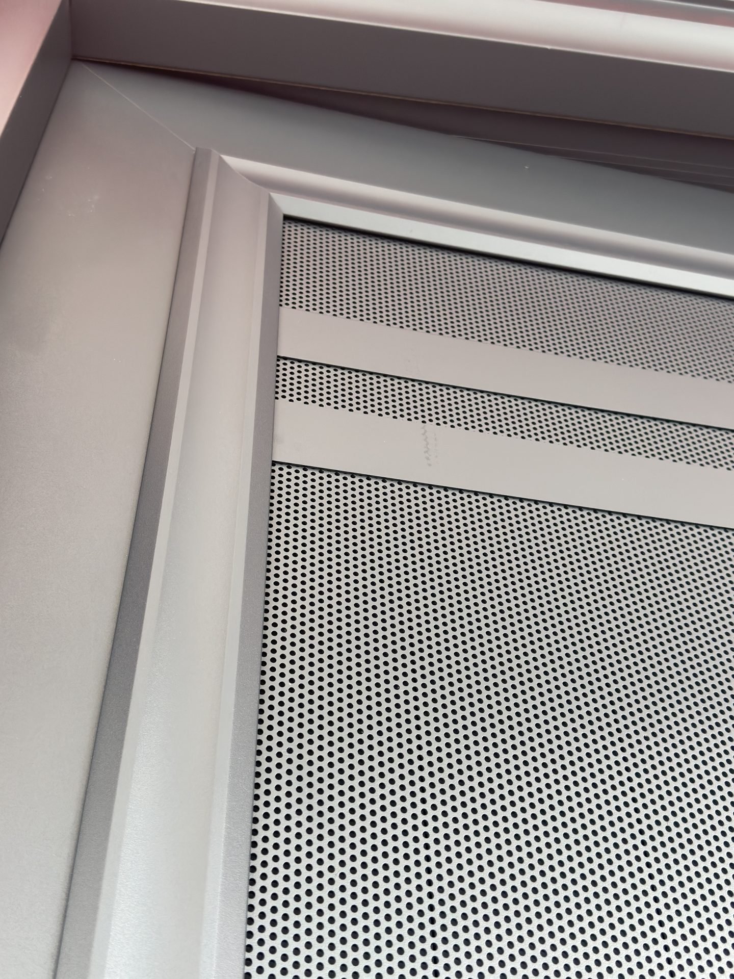 Close-up of a perforated aluminium sheet allowing airflow through a security door